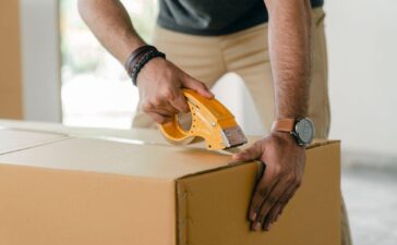 A man tapping a cardboard box with scotch