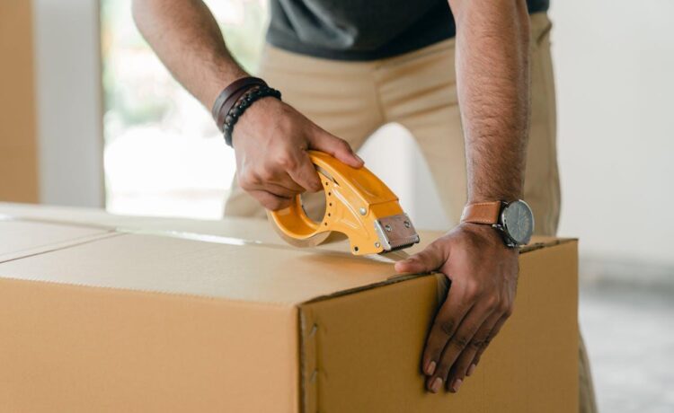 A man tapping a cardboard box with scotch