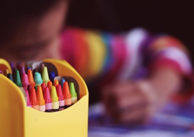 Picture of a kid that is using crayons 