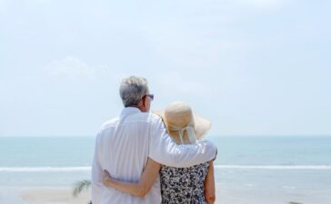 A senior couple looking at the sea from a balcony.