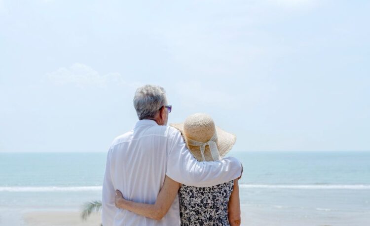 A senior couple looking at the sea from a balcony.